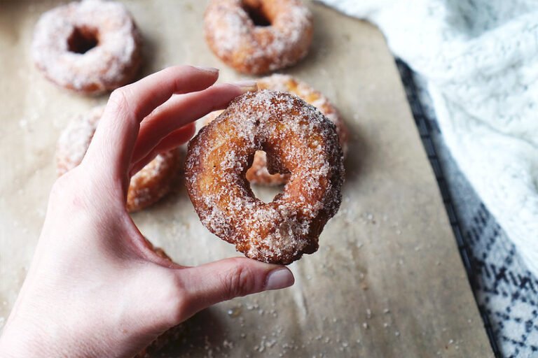 Hand holding a cinnamon sugar churro donut